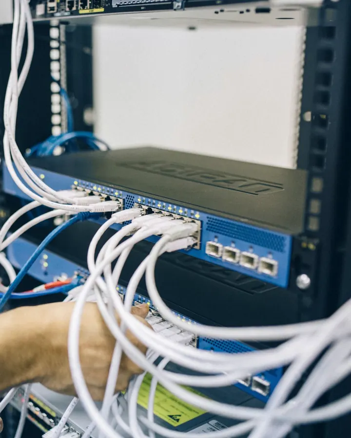 Network engineer patching cables into a switch in a server rack
